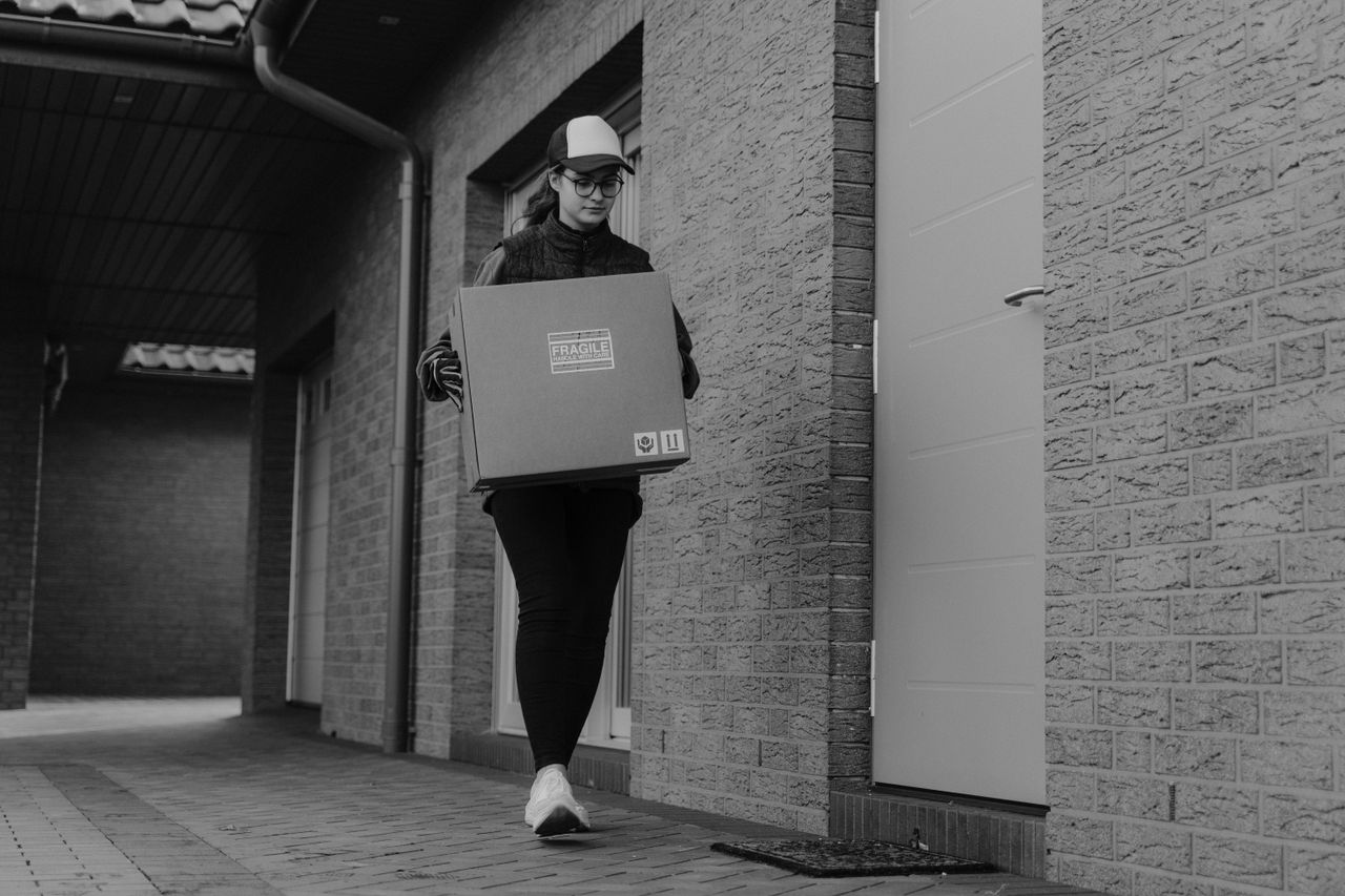 Courier delivering a package outdoors in a monochrome setting.